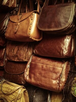 A collection of vintage leather bags in various styles and colors showcased in a market stall.